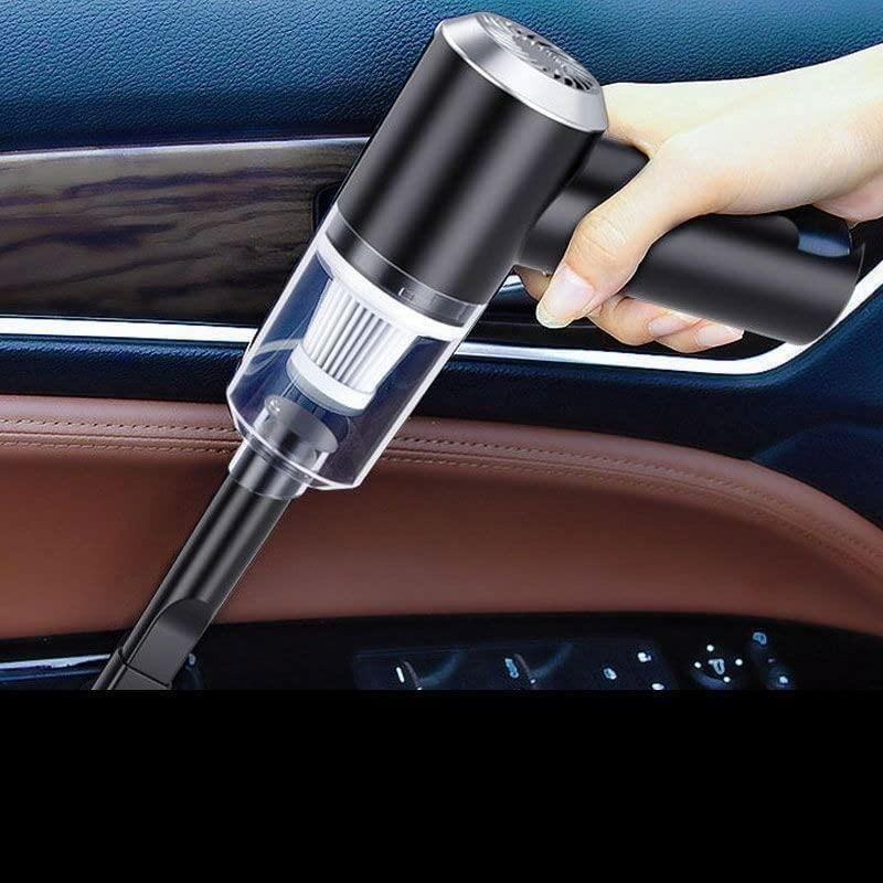 Hand holding a black and silver car vacuum cleaner inside a vehicle.