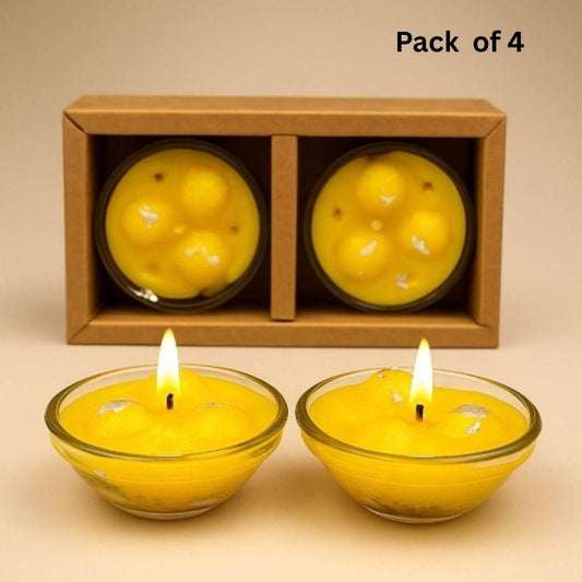 Two lit yellow candles in glass holders with a wooden box containing two more candles on a beige background.